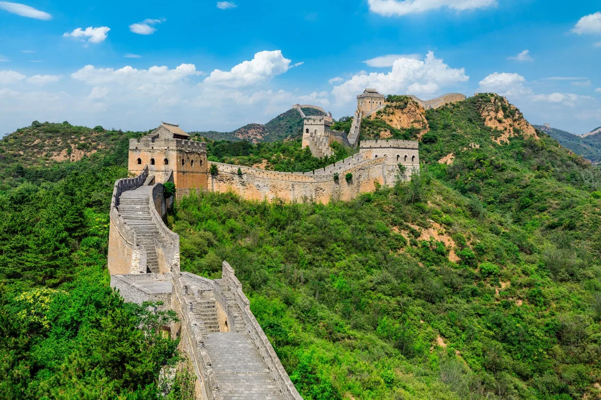 The Great Wall winding through lush green hills under a blue summer sky